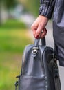 Elegant outfit. Close up of stylish gray backpack in woman s hand. Model holding bag and sitting on the green grass Royalty Free Stock Photo