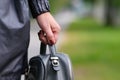 Elegant outfit. Close up of stylish gray backpack in woman s hand. Model holding bag and sitting on the green grass Royalty Free Stock Photo