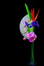 Heliconia flower blue iris and pink phalaenopsis orchid flowers in a tall crystal vase on black background Royalty Free Stock Photo