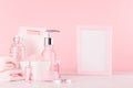 Elegant pink skin and body care products - cream, rose oil, liquid soap, salt, cotton towel and box on wood table, blank frame. Royalty Free Stock Photo