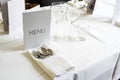 Elegant place setting with menu card, various glasses, cutlery and napkin on a table with white tablecloth for a festive dinner, Royalty Free Stock Photo