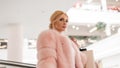 Elegant portrait pretty luxurious young woman with blond hair in chic pink expensive fur coat in mall. Sexy business girl model is