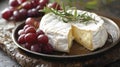 Elegant presentation of Brie cheese with fresh red grapes and rosemary Royalty Free Stock Photo