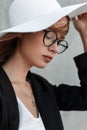 Elegant pretty beautiful portrait young girl in fashion glasses in summer stylish straw hat in black blazer on gray background Royalty Free Stock Photo