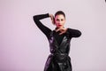 Elegant pretty sexy young brunette woman with stylish hairstyle with red chic lips in fashionable leather dress posing near a Royalty Free Stock Photo