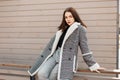 Elegant pretty young woman in a vintage gray checkered jacket in a black T-shirt in stylish pants sits and relaxes on a spring day Royalty Free Stock Photo