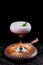 Elegant red ladies` cocktail with pink foam in a beautiful glass on a wooden carved round board Royalty Free Stock Photo