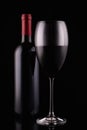 Elegant red wine glass and black wine bottle on black  background Royalty Free Stock Photo