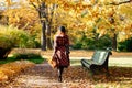 redhead woman in plaid coat and beret walks through the park at sunny day, back view. fall season Royalty Free Stock Photo