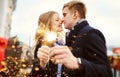 Elegant romantic couple with sparkle in hands hugging and kissing on festive city decorations background. Royalty Free Stock Photo