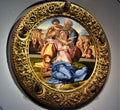 Elegant round and golden frame from which five heads come out, with painting of woman child and old man, at the Uffizi museum in F