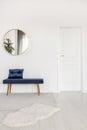 Elegant round mirror above velvet bench in white waiting room interior