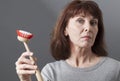 Elegant 50s woman handing over dish brush for washing and cleaning at home Royalty Free Stock Photo