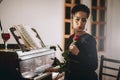 Elegant and sad woman touching the piano keyboard with one hand and holding rose Royalty Free Stock Photo