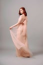 Elegant salmon dress. Beautiful peach chiffon evening gown. Studio portrait of young brunette woman.