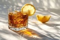 Elegant Sazerac cocktail with ice and lemon peel in stark sunlight
