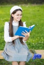 Elegant schoolgirl child girl reading book in park, french language concept Royalty Free Stock Photo