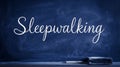 Elegant script word Sleepwalking written on a dark blue chalkboard with chalk dust visible Royalty Free Stock Photo