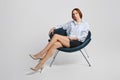 Elegant senior woman in mini skirt and white sits in armchair