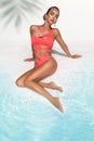 Elegant sexy woman in bikini on the sun-tanned slim and shapely body is posing near the swimming pool. Sunbathing By Swimming Pool Royalty Free Stock Photo