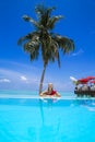 Elegant sexy woman in the red bikini on the sun-tanned slim and shapely body is posing near the swimming pool on Maldives. Perfect Royalty Free Stock Photo