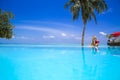 Elegant sexy woman in the red bikini on the sun-tanned slim and shapely body is posing near the swimming pool on Maldives. Perfect Royalty Free Stock Photo