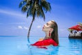 Elegant sexy woman in the red bikini on the sun-tanned slim and shapely body is posing near the swimming pool on Maldives. Perfect Royalty Free Stock Photo