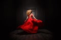 Elegant and woman in the red evening fluttering dress is capture in move, running away from the ceremony