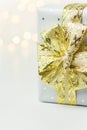 Elegant silver gift box tied with golden ribbon bow bokeh garland lights on white background. Christmas New Years presents holiday Royalty Free Stock Photo