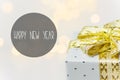 Elegant silver gift box tied with golden ribbon with bow bokeh garland lights on white background. Happy New Year greeting card Royalty Free Stock Photo