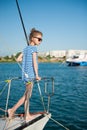 Elegant slim little girl in sunglasses aboard luxury yacht