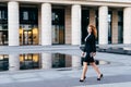 Elegant slim woman in black suit and high-heeled shoes, holding tablet in hands going for work. Businesswoman in motion. Confident Royalty Free Stock Photo