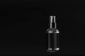 Elegant small transparent spray dispenser bottle for cosmetics with black label on dark black background, mock up for branding.