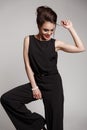 Elegant and smartly dressed smiling woman with collected hair, red lips and smoky eyes is posing in the studio