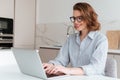 Elegant smiling woman in glasses and striped shirt using laptop Royalty Free Stock Photo