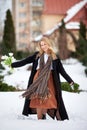 Elegant smiling young woman with long blonde hair in a black coat poses in the city. Winter portrait of a beautiful modern woman Royalty Free Stock Photo