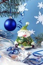 Elegant snowman among Christmas balls and Christmas tinsel on a blue background, side view, vertical frame Royalty Free Stock Photo