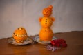 Elegant snowman from tangerines in a red cap from carrots in a saucer and a red toad from bell pepper on a wooden table Royalty Free Stock Photo