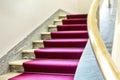 Elegant staircase with a purple velvet carpet on the steps and a brass handrail Royalty Free Stock Photo