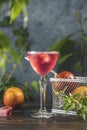 Elegant stemware glass of blood orange cocktail with frozen raspberries in ice cube on dark wooden table surface Royalty Free Stock Photo