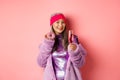 Elegant and stylish asian woman in purple faux fur coat eating donuts and drinking champagne, having fun at party