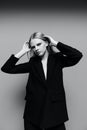 An elegant stylish girl tucks her hair behind her ears and raises her hands up. A stylish lady in a suit poses in the Royalty Free Stock Photo