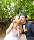 Elegant stylish groom and happy gorgeous bride have fun with bubble blower outdoors in park Royalty Free Stock Photo