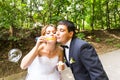 Elegant stylish groom and happy gorgeous bride have fun with bubble blower outdoors in park Royalty Free Stock Photo