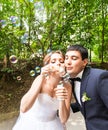 Elegant stylish groom and happy gorgeous bride have fun with bubble blower outdoors in park Royalty Free Stock Photo