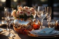 Elegant summer table with white plates and tissues, wine glasses, flowers in a golden pot, on a gold colored surface and a blurred