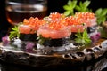 Elegant sushi roll topped with fresh salmon, roe, and garnish on a sleek black plate