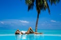 Elegant tanned woman in white swimsuit in pool on tropical Maldives island. Beautiful bikini body girl in pool with view on Royalty Free Stock Photo