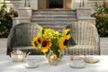 Elegant tea serving in garden with sunflowers in vase on marble table with silver tea pot and cookies Royalty Free Stock Photo