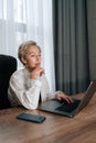 Elegant thoughtful middle-aged adult businesswoman working on laptop computer looking to screen, thinking solving Royalty Free Stock Photo